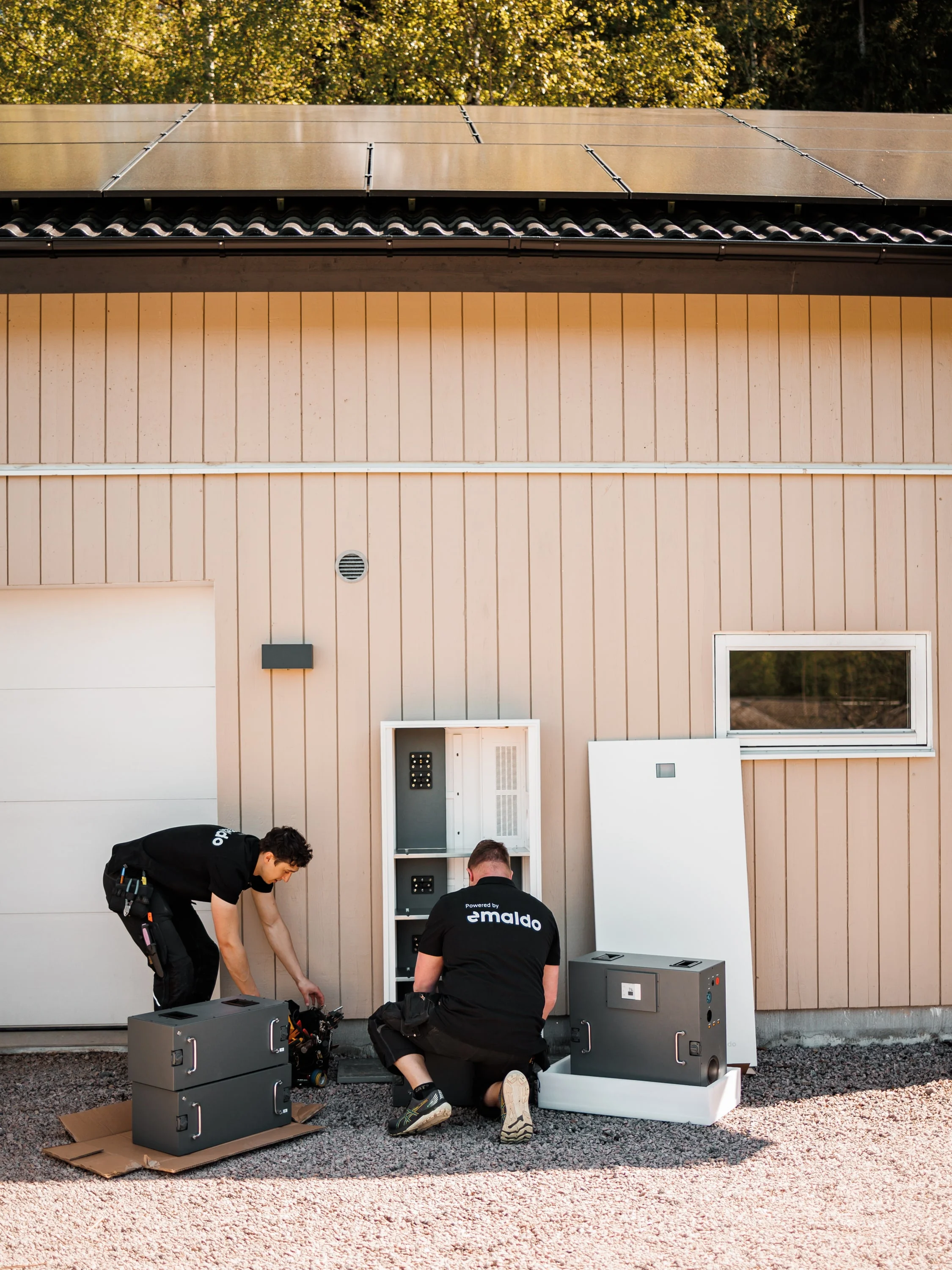 Två montörer installerar batterier vid en byggnad